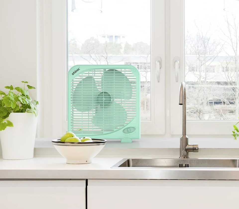 Green tabletop fan by a kitchen window